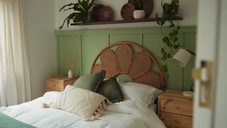 dolly shot reveals neatly arranged bedroom with green themed decor. the calming tones of plants, cushions and bedding blend seamlessly, creating fresh peaceful ambiance in cozy space