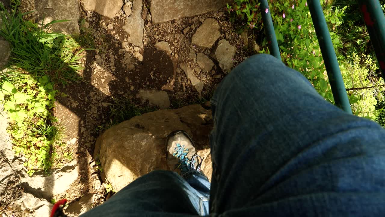 imágenes pov: hombre caminando con vaqueros y botas de senderismo en un sendero rocoso