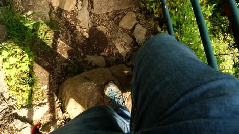 imágenes pov: hombre caminando con vaqueros y botas de senderismo en un sendero rocoso