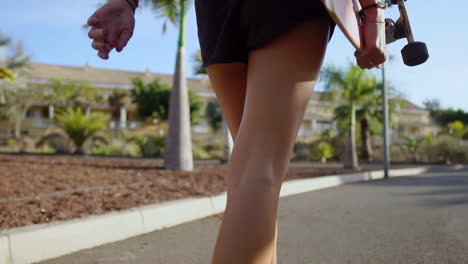 caminando hacia el parque en medio de las palmeras, dos amigos llevan patinetas, compartiendo conversación, risas y sonrisas llenas de alegría, sus movimientos ralentizados por los encantadores tonos de la puesta de sol