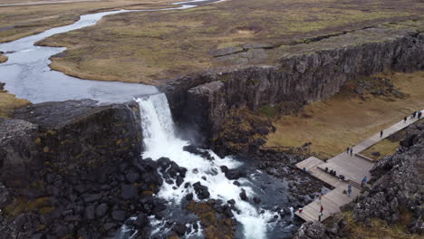 cascada de oxarafoss en islandia, con turistas.