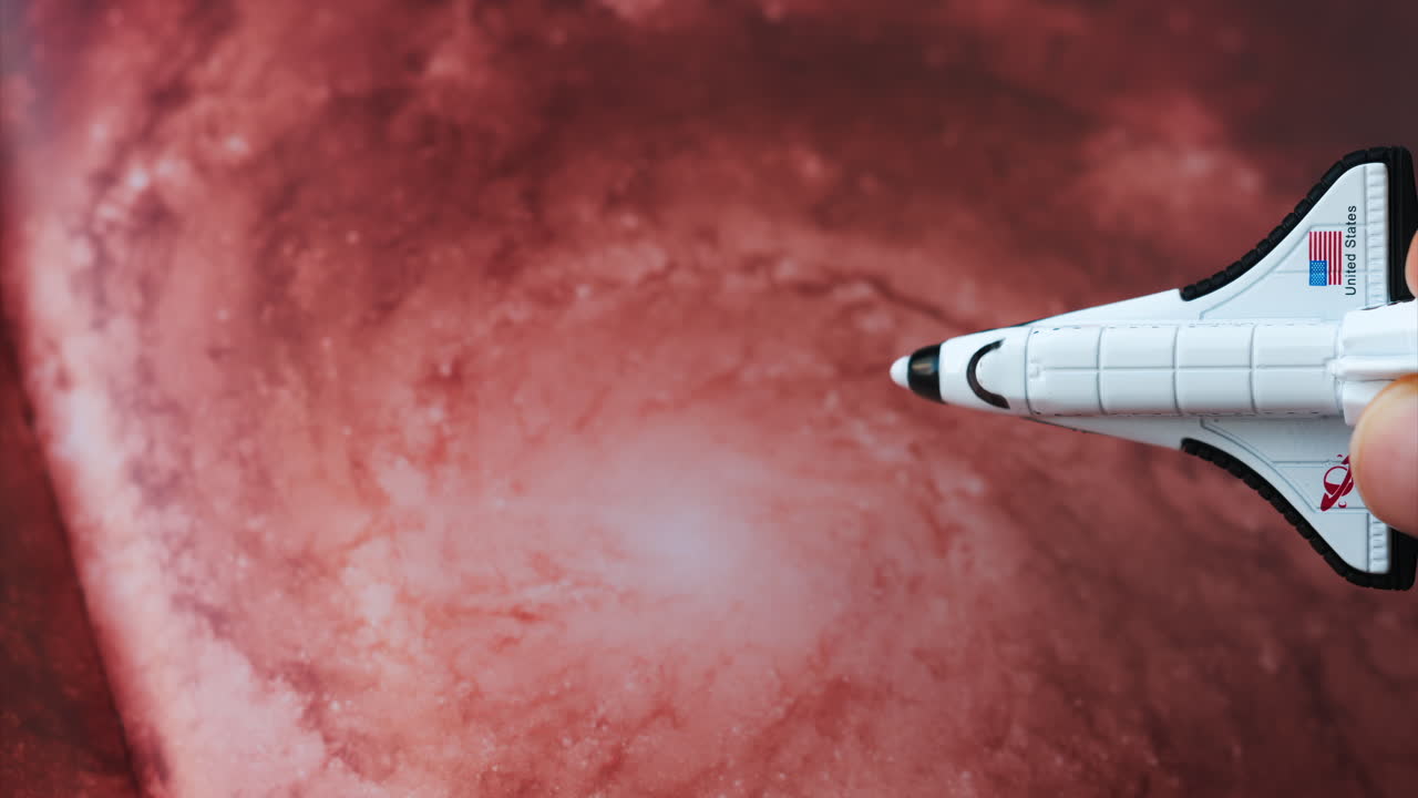 Primo piano di un modellino di navicella spaziale giocattolo su uno sfondo galattico rossastro