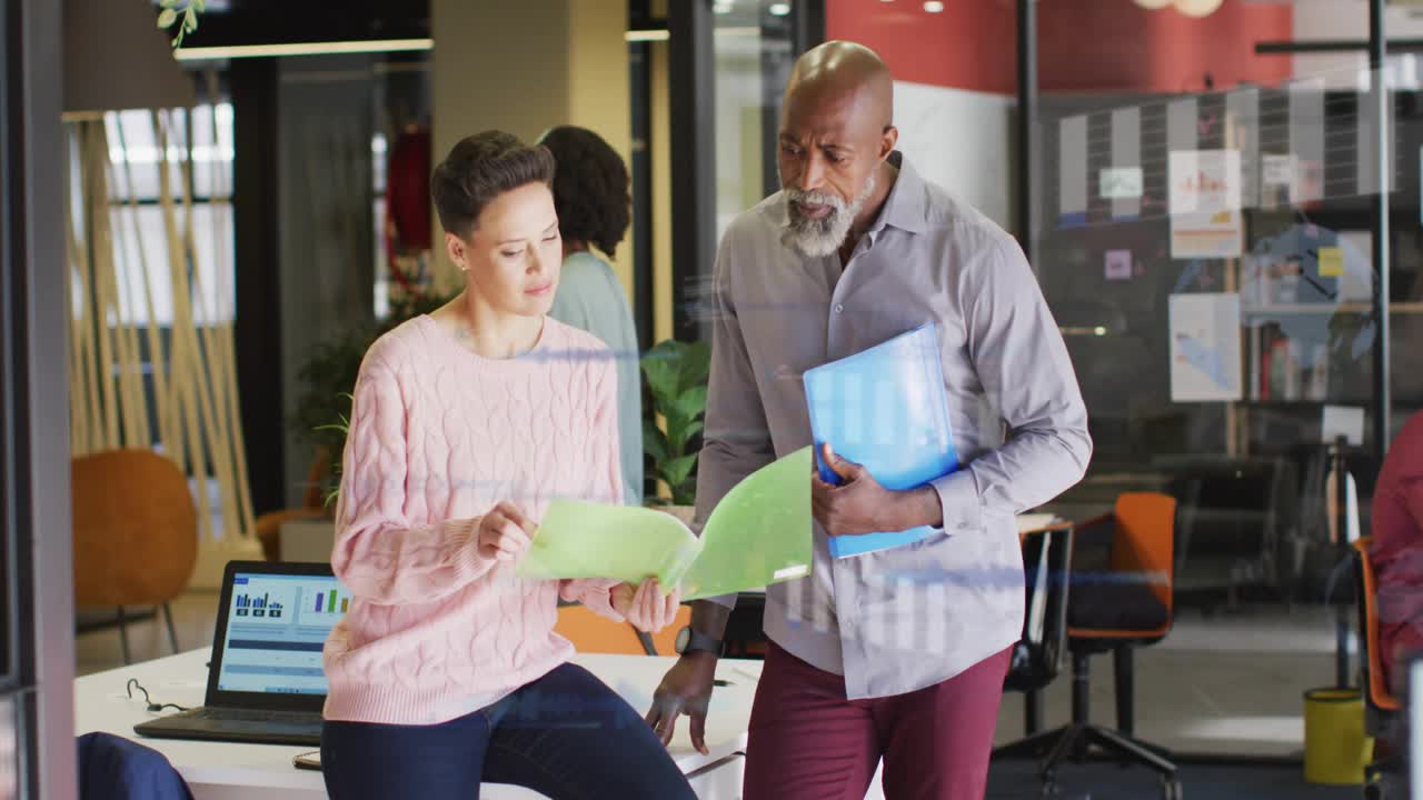 Team flipping green folder, creating faint chart overlay on laptop while reviewing business metrics