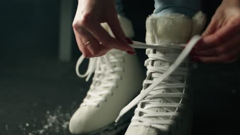 slowmotion de mãos de patinadora de gelo mulher fazendo um nó em uma renda de patinação de gelo branca com calças de ganga azuis