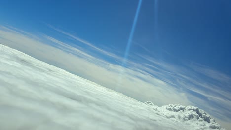 an immersive flight experience through the pilot’s eyes from inside a jet cockpit, while flying in a left turn over an endless sea of clouds and sun rays reflecting through the windshield.