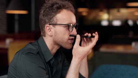 stylish curly man with glasses sitting in a cafe talking on the phone