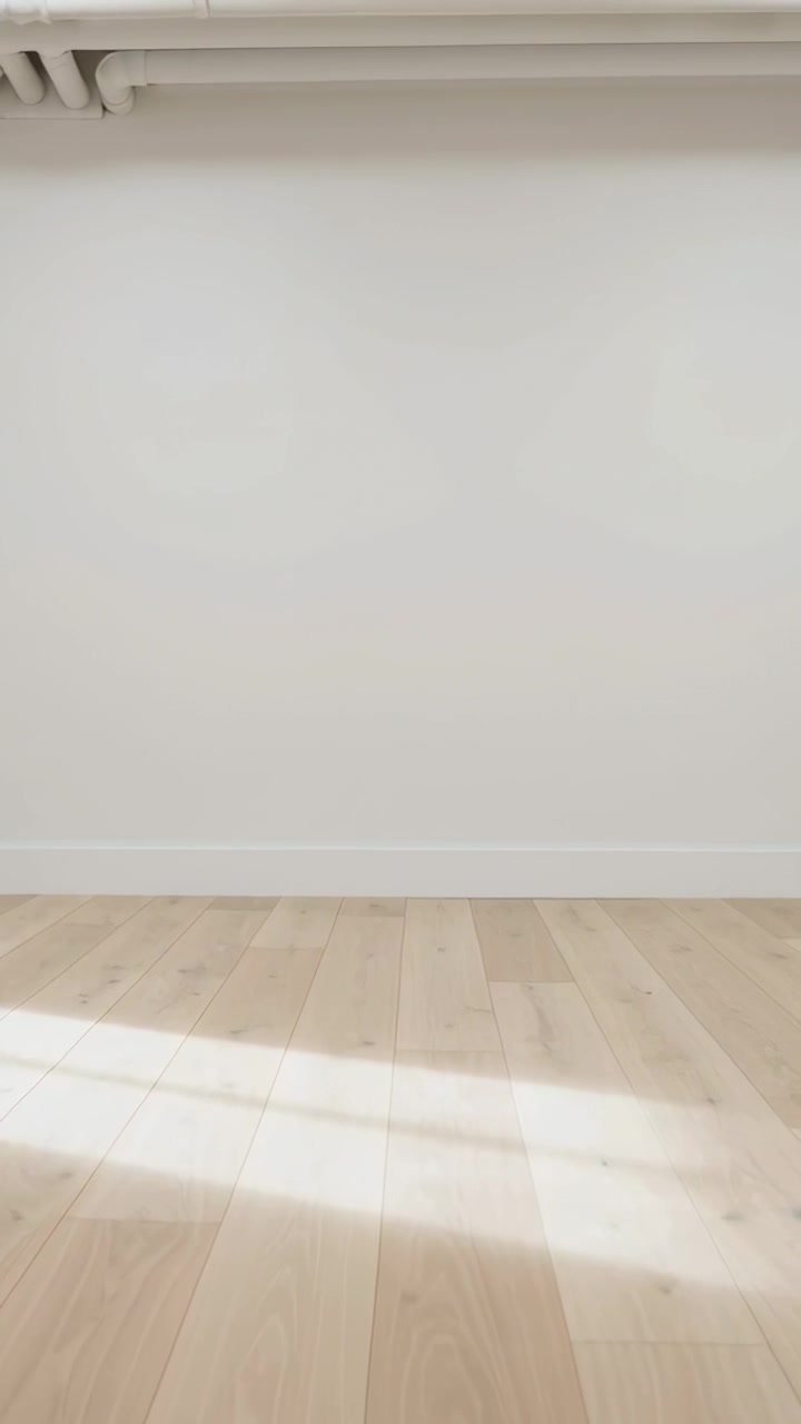 Vertical video: Shifting low camera revealing wood floor and sunbeam in room exposing ceiling pipes