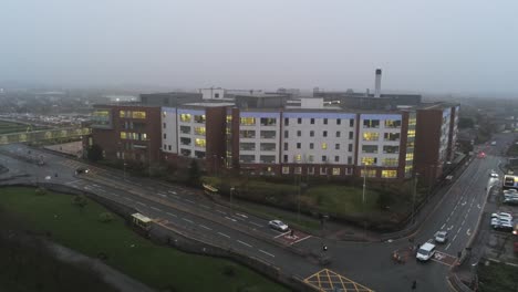 misty foggy hospital building uk town traffic aerial view low angle orbit right