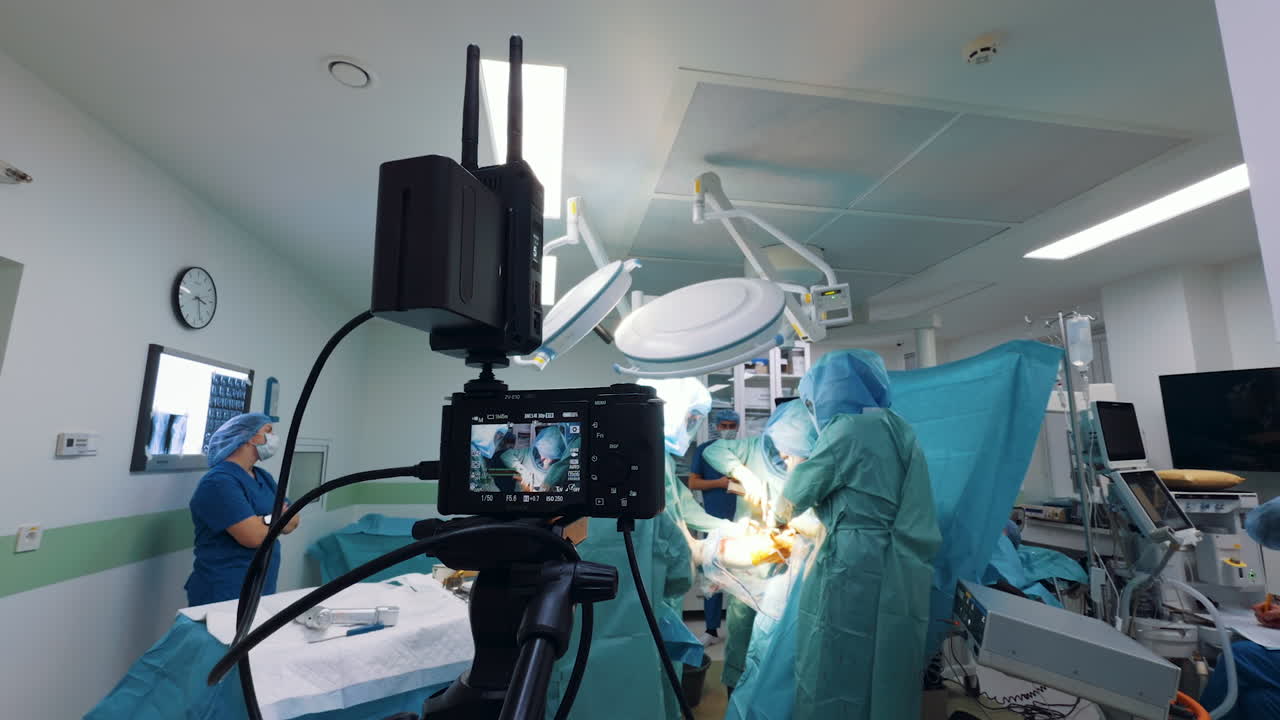 Kyiv, Ukraine, 2 August 2025: Wide angle shot of a camera filming a surgery, with a scribe seated below the patient. The high-tech equipment captures the team working under bright operating lights, with a medical professional taking notes