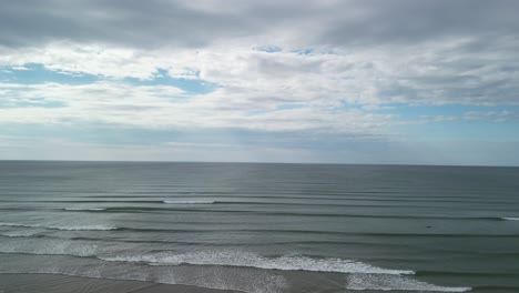 an aerial lift of over calm atlantic ocean with incoming waves in the morning