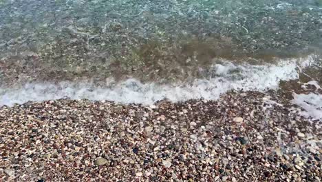 cobble beach in rhodos, greece with marmaris in the far end, blue crystal clear water, travel destination and establishing shot filmed in 4k