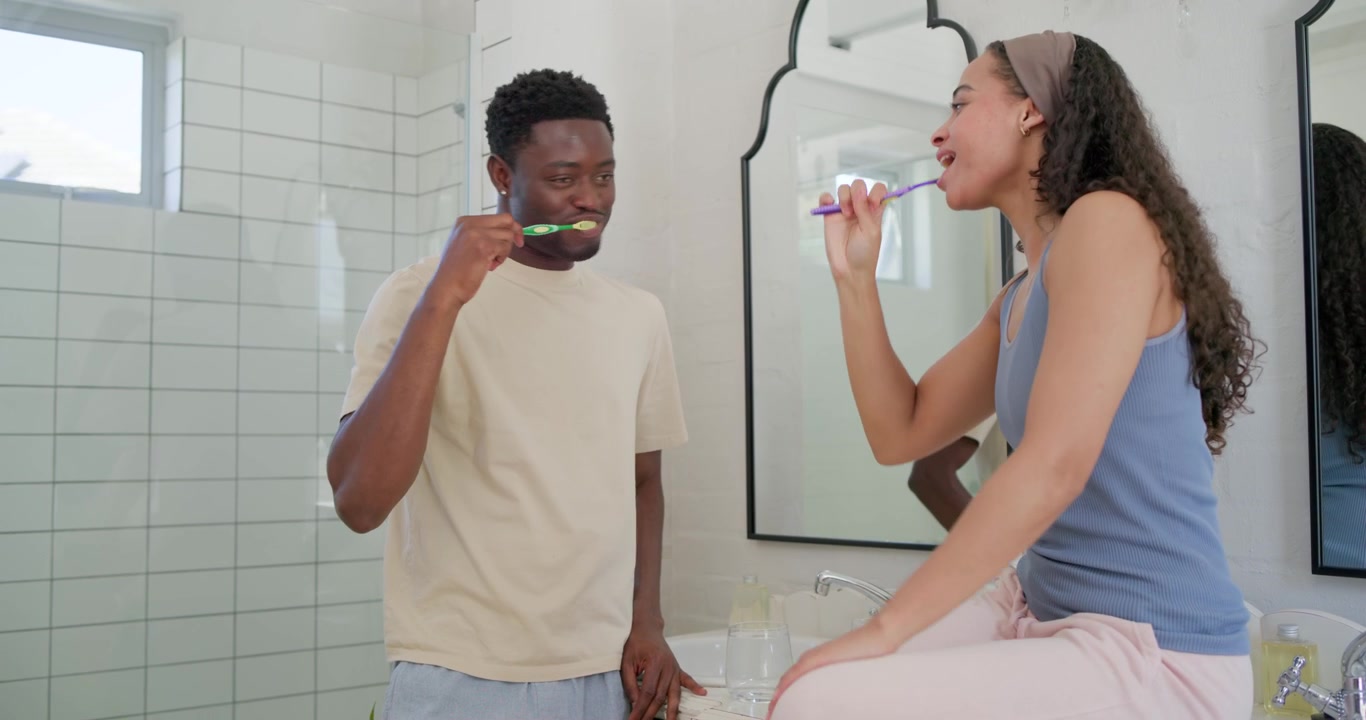 African American couple during morning routine, man squeezing paste onto brush while both brushing