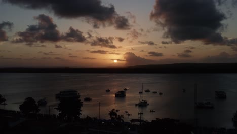 aerial shot of the alligator beach, a river in cabedelo, paraiba, brazil, near the coastal capital city of joao pessoa, with a group of tour boats watching the sunset as a man plays the saxophone