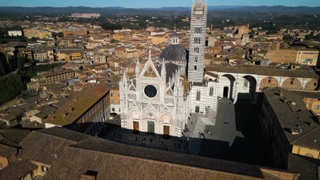 forward drone shot above siena cathedral on beautiful day in italy's tuscan region