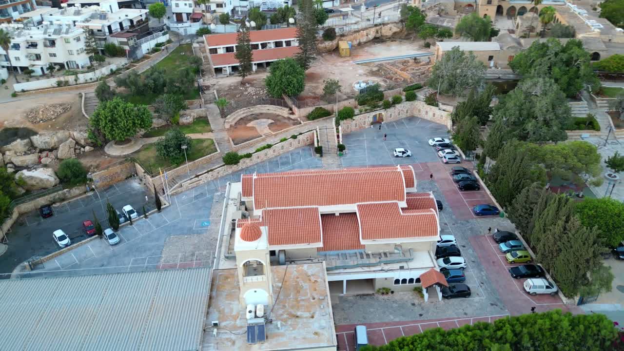 Daytime aerial of Church of St. George in Aya Napa, Cyprus with terracotta roof and gardens, establishing overview