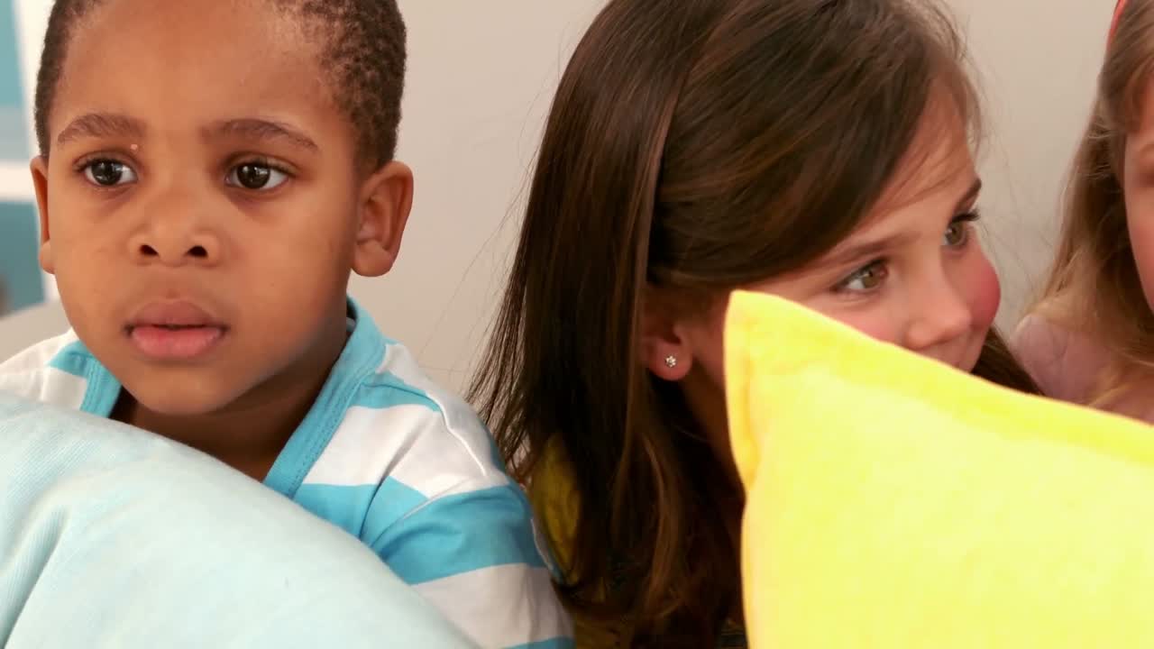 아이들이 베개와 함께 소파에 앉아 있습니다.