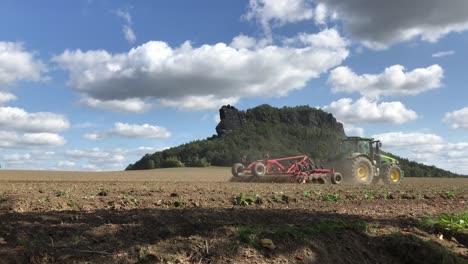 Tractor-ploughing-dry-and-dusty-farm-crop,-ground-level-view