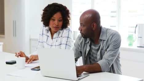 Man-using-laptop-while-woman-calculating-bills-4k