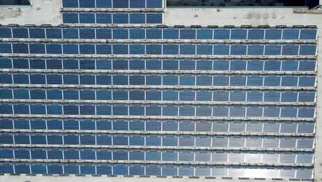 top down aerial of soloar panels on roof of large high school - drone lifting up