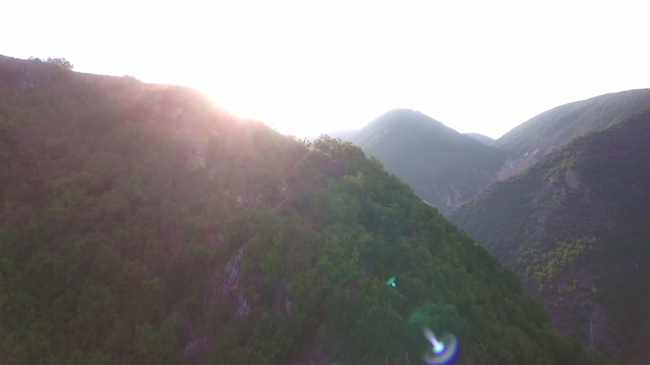 세르비아 유럽의 노비 파자르 외곽 산 뒤의 태양 광선, 공중 오름차순 및 팬 왼쪽