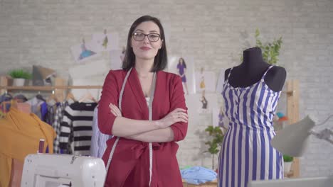 portrait of a young woman fashion designer in glasses with a tape measure in a modern workshop