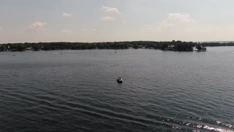 Aerial-view-circling-boat-in-the-middle-of-a-lake-during-summer,-4k-drone-footage