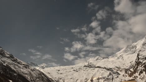 Timelapse-during-a-sunrise,-clouds-pass-over-the-snowy-mountains-of-saas-fee-during-the-winter