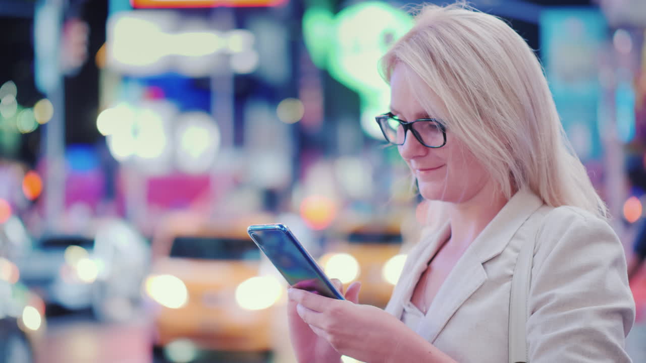 mujer de negocios usa un teléfono inteligente en la concurrida times square en nueva york están pasando los famosos taxis amarillos