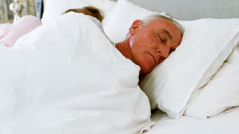 Senior-man-sleeping-besides-woman-on-bed