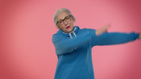 Trendy-positive-elderly-woman-having-fun-dancing,-dabbing-raising-hands,-making-dubdance-gesture