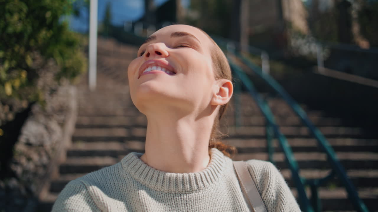 Primo piano di una donna sorridente in piedi sulle scale al sole che legge appunti in un quaderno