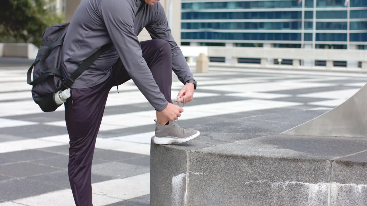 Noticing loose laces man bending on concrete ledge in plaza retying sneaker laces securing shoes