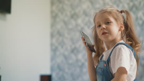 little girl with ponytails talks on smartphone in light room