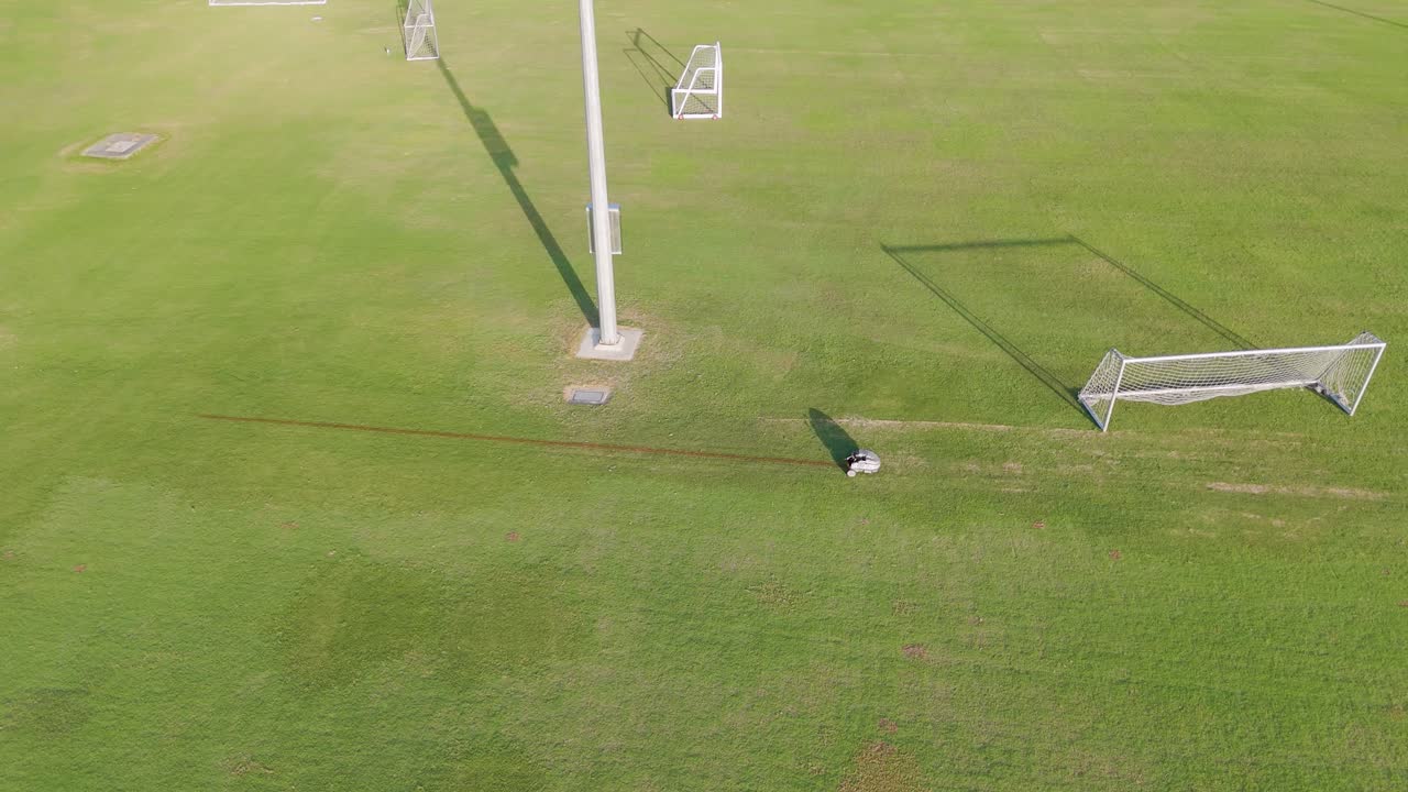A robot autonomously paints lines on a soccer field under bright daylight, showcasing automation in sports field maintenance