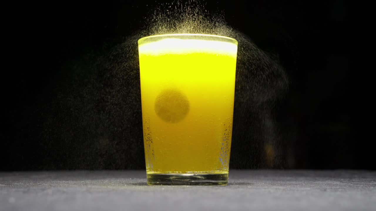 un vaso de bebida efervescente con sabor a naranja con pastillas de vitaminas flotantes y fondo negro