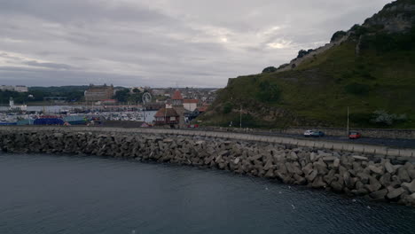 rising establishing drone shot over scarborough harbour and seaside town on overcast morning