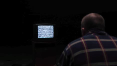 man watching a television with static noise