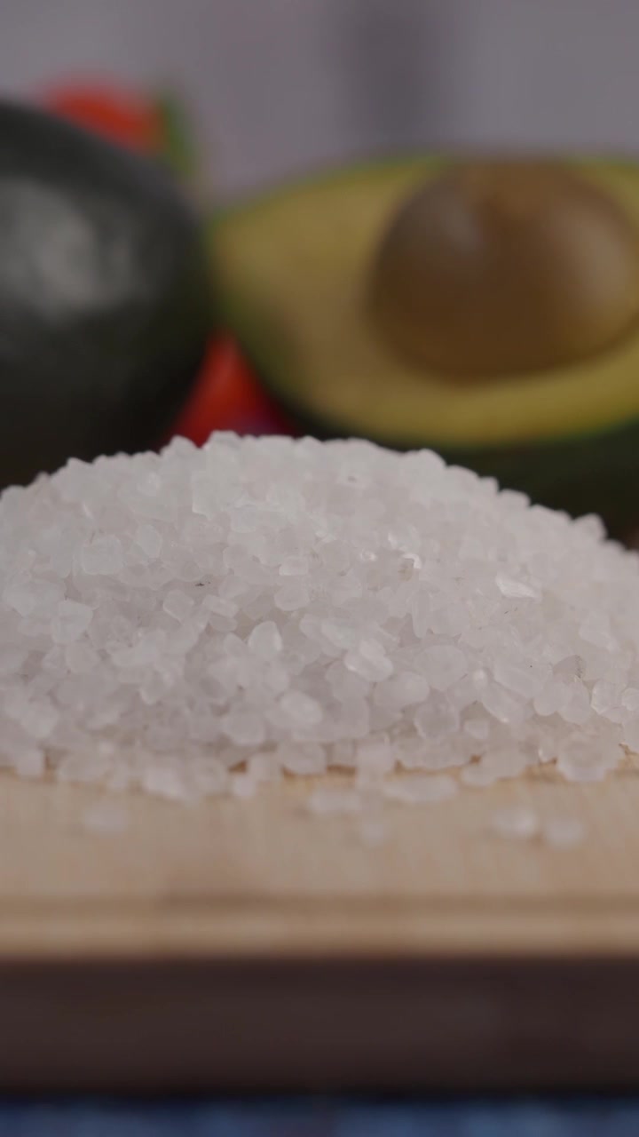 Primer plano de sal marina gruesa sobre una tabla de madera con aguacates