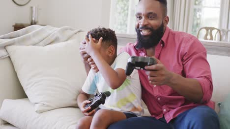 feliz padre e hijo afroamericanos viendo jugar videojuegos juntos, en cámara lenta