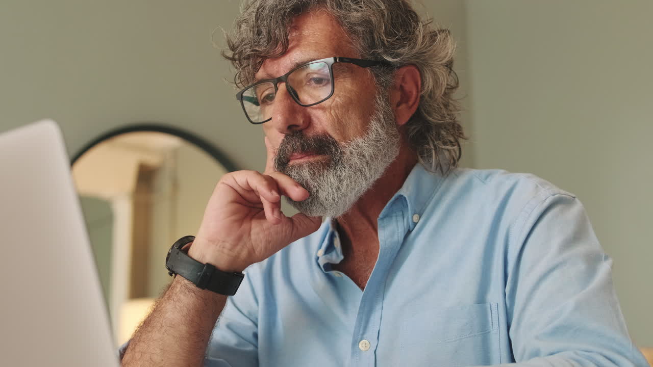 Mature Man with Beard and Glasses Working on Laptop