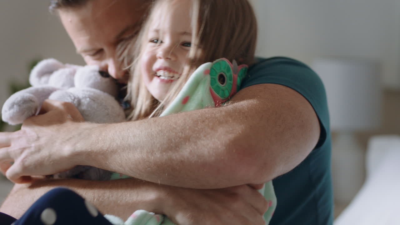 pai feliz abraçando filha na cama menina rindo desfrutando abraço de pai pai amoroso abraçando criança se divertindo manhã de fim de semana em casa