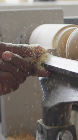 craftsman shapes wood on a lathe in a workshop