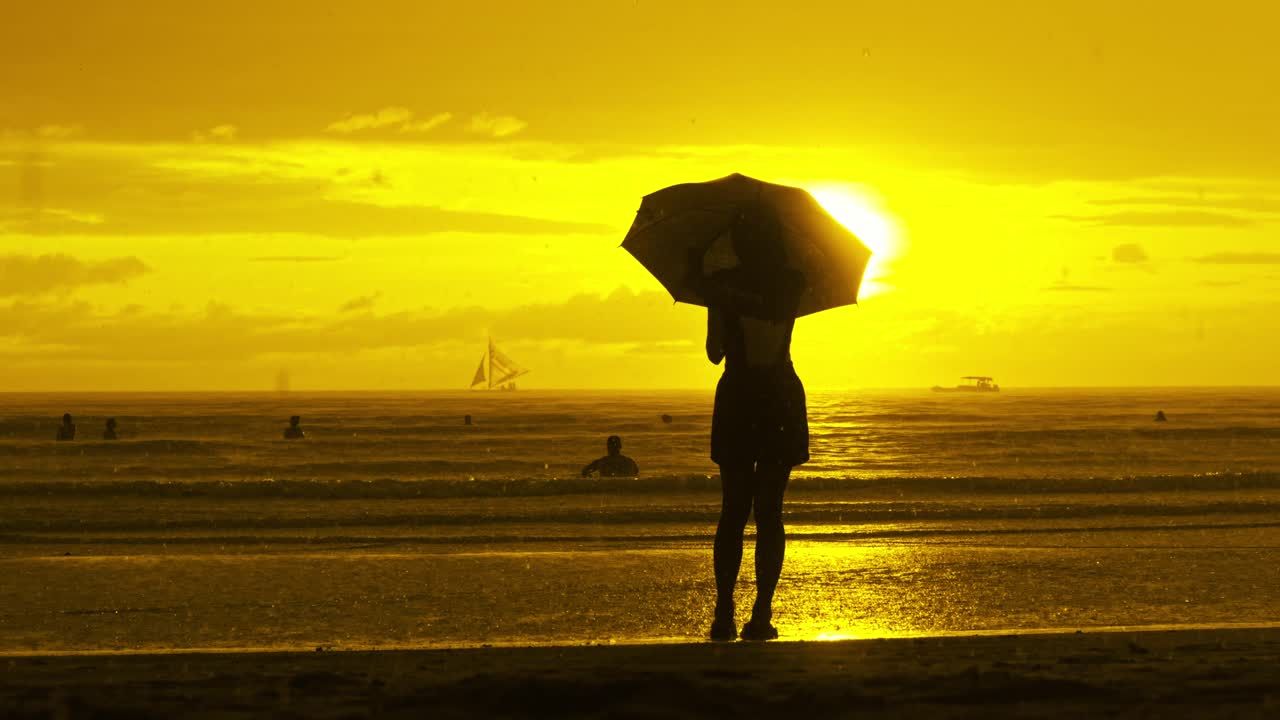 Silhueta de mulher com guarda-chuva na chuva, pôr do sol dourado espetacular na praia de Boracay.