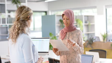 Diverse-creative-female-colleagues-in-discussion-using-documents-in-office,-slow-motion