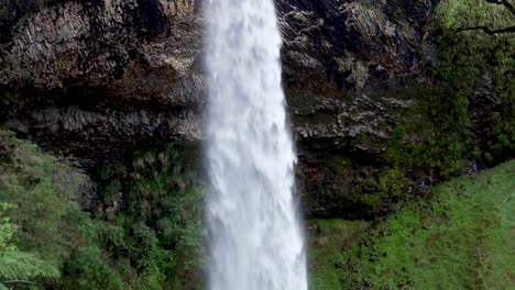 watching the stunning bridal veil falls waterfall surrounded by forest and huge cliffs on a day hike in raglan, new zealand aotearoa