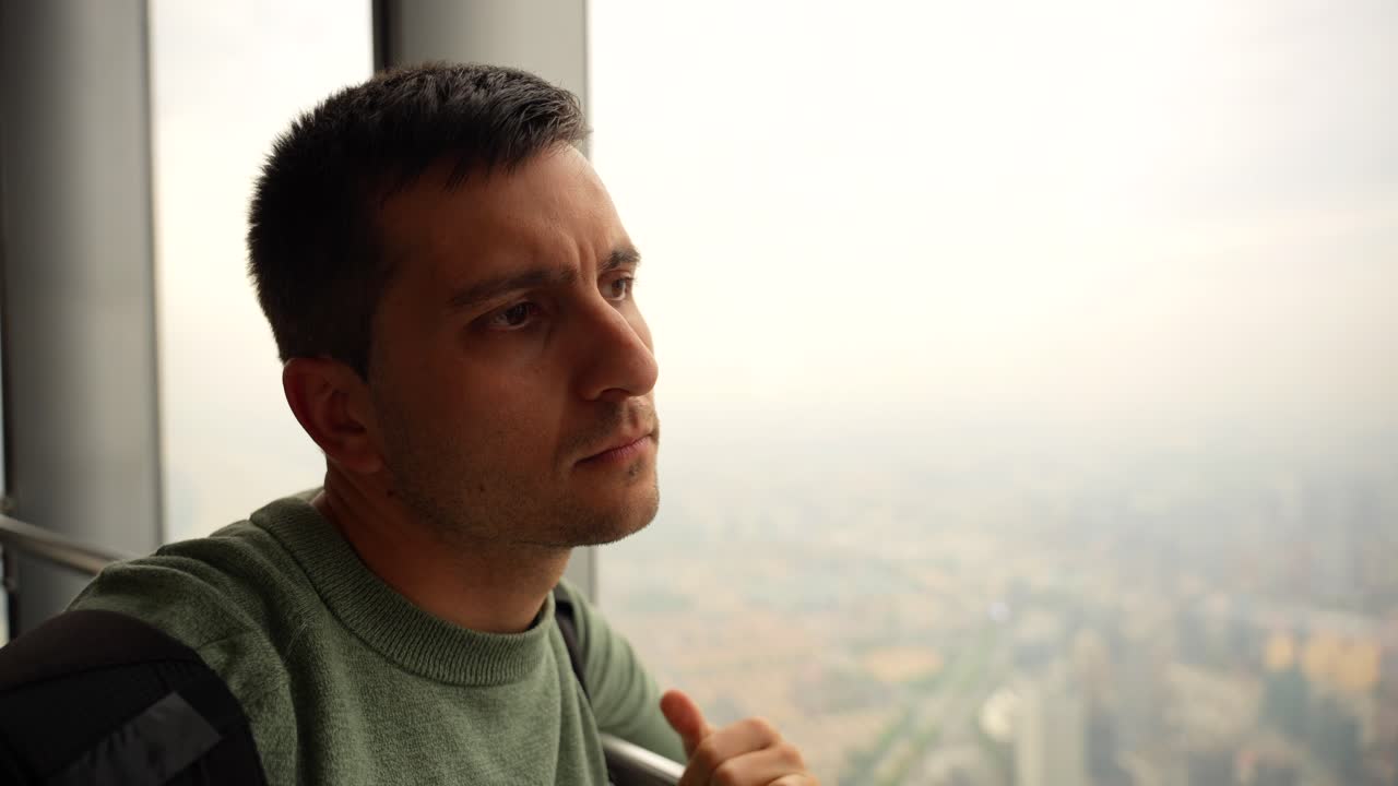 Man observing city view from Shanghai Tower viewpoint with smog on a cloudy day