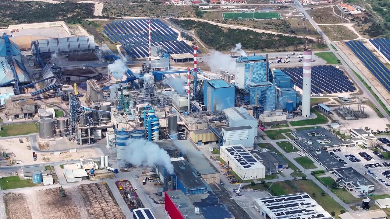 Extensive industrial complex featuring a pulp and paper mill alongside a biomass facility with solar panels, producing renewable energy