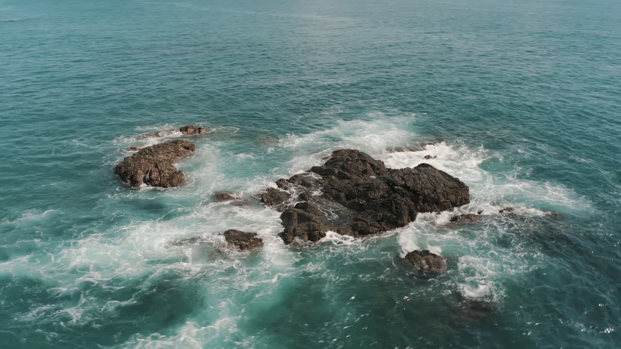 giro aéreo de drones y olas rompiendo en las rocas en el océano de costa rica