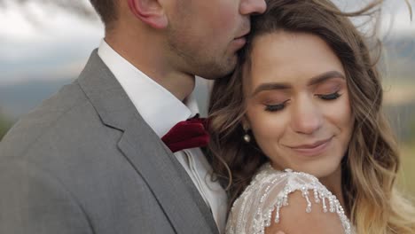 lovely young newlyweds bride and groom embracing, hugging on mountain slope, wedding couple in love