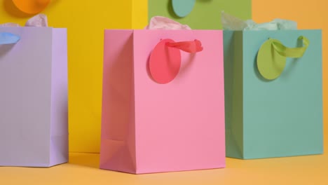 studio shot of colourful birthday party gift bags against yellow background